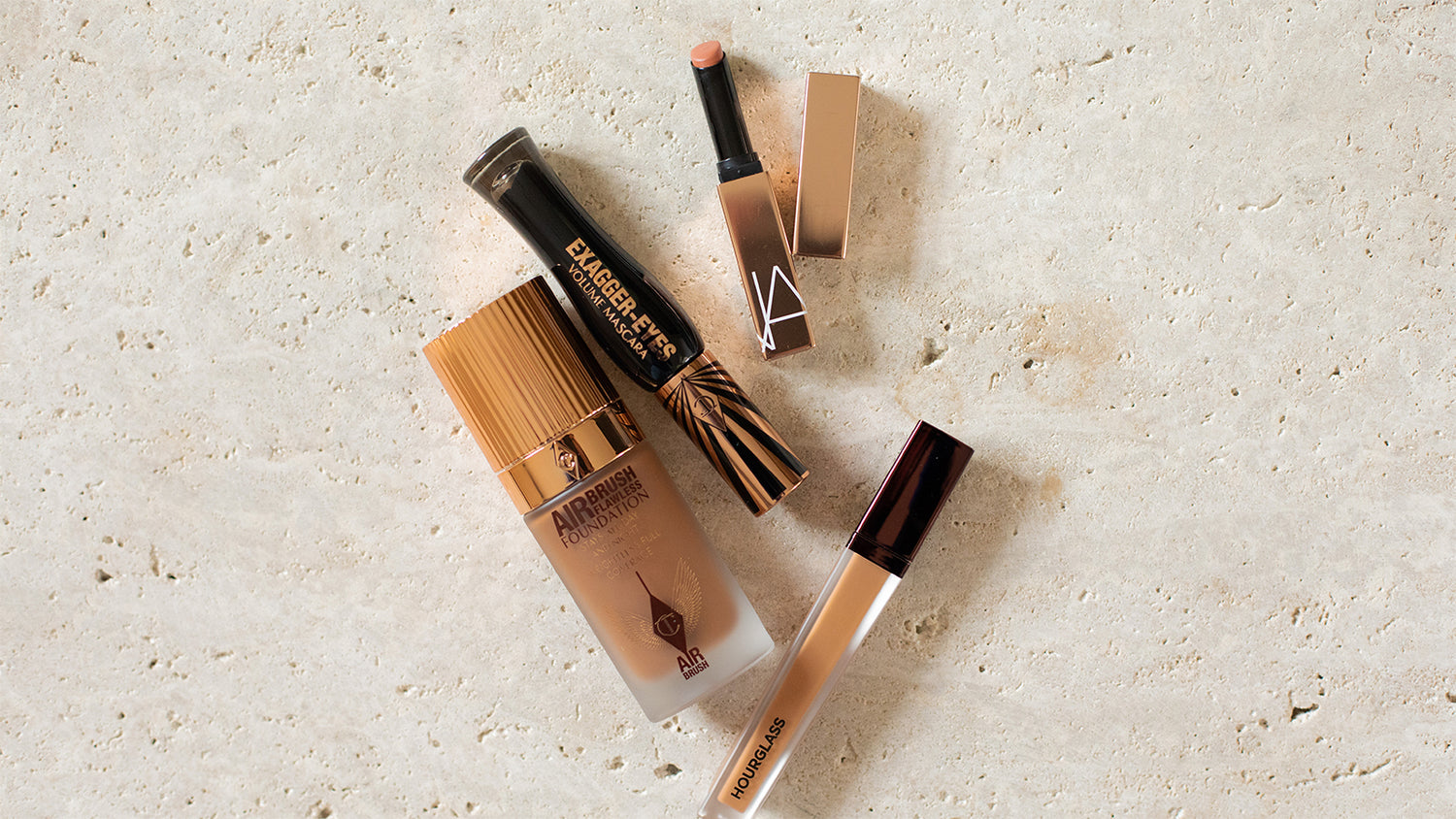 Makeup products including a concealer and a brush on a light surface