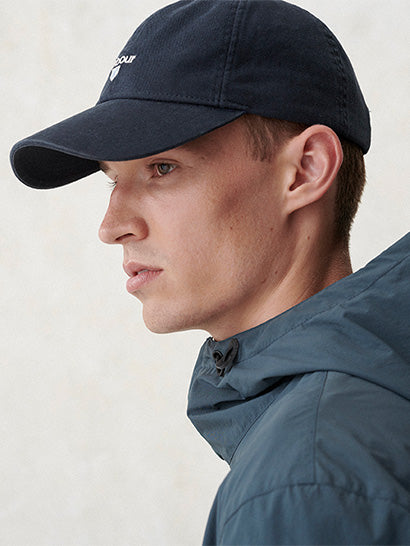 Man wearing a navy cap and blue jacket against a light background