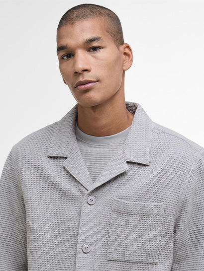 Man wearing a textured grey shirt against a plain background
