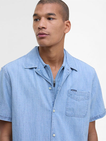 Man wearing a light blue Barbour denim shirt against a plain background